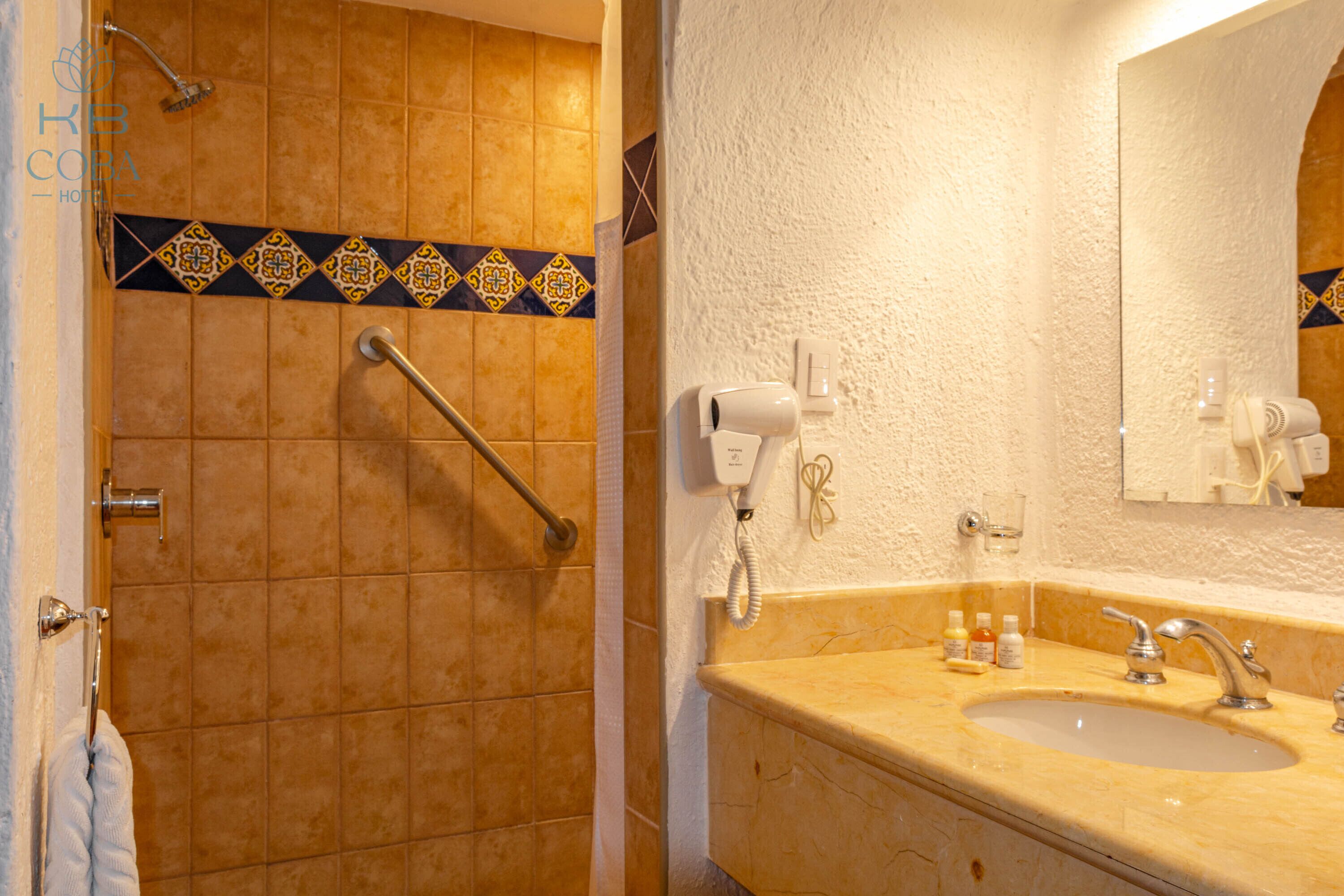 Een badkamer met een beige wastafel, een spiegel en een douchegedeelte met een handgreep.