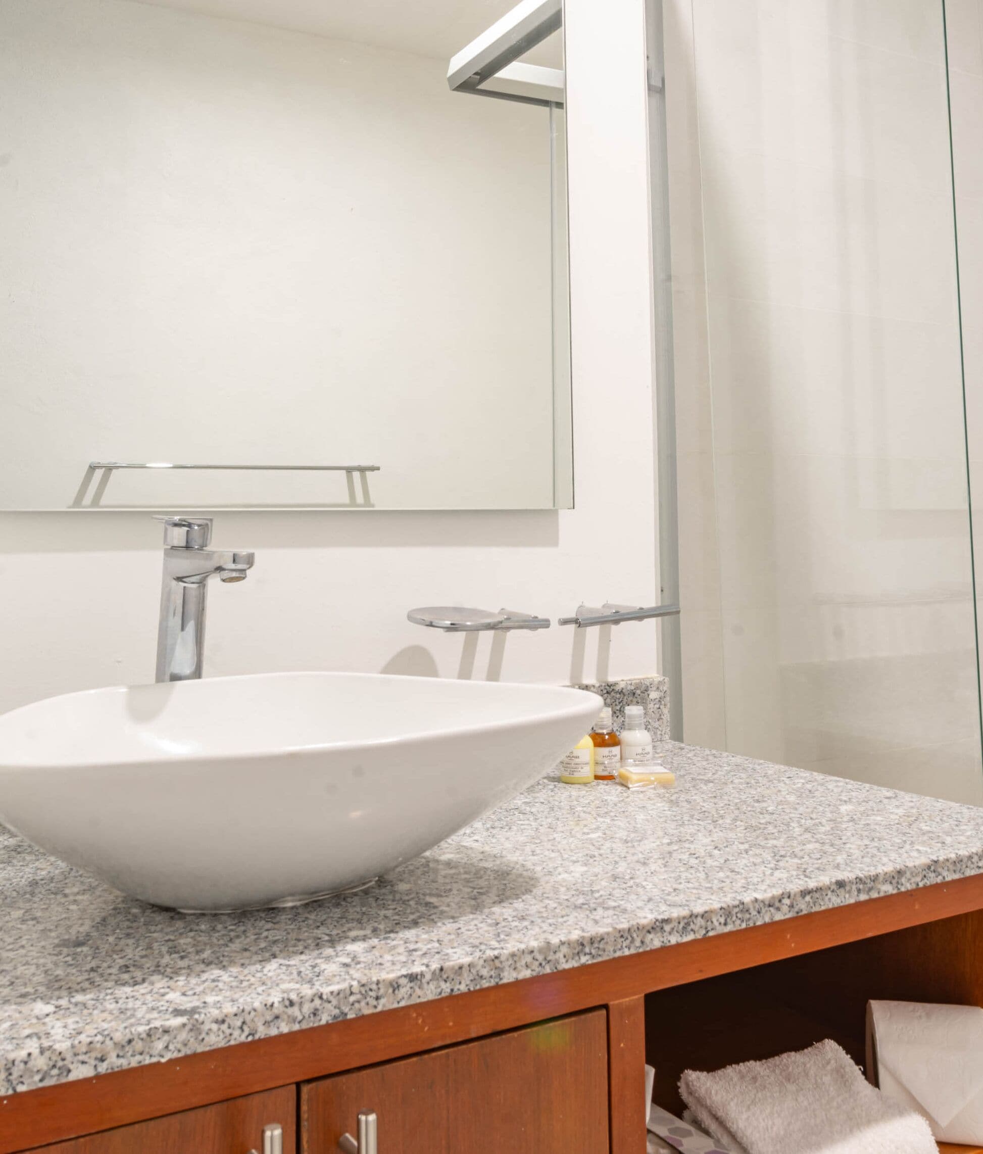 A bathroom with a large white sink, a mirror, and a granite countertop.
