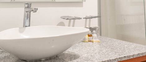A bathroom with a large white sink, a mirror, and a granite countertop.