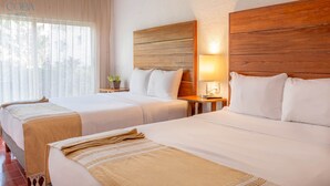 A hotel room with two beds, wooden headboards, a bedside table with a lamp, and a window with sheer curtains. - Kaab Coba (Coba)