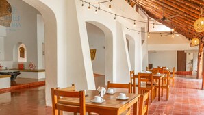 A spacious dining area with wooden tables and chairs, white walls, and a tiled floor. - Kaab Coba (Coba)