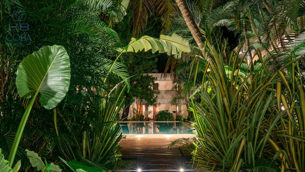 A tropical garden pathway leading to a pool area with lush greenery and a wooden deck. - Kaab Coba (Coba)