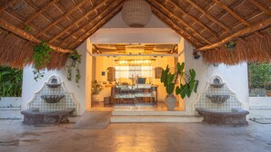 A thatched-roof structure with a central seating area, a small fountain, and potted plants. - Kaab Coba (Coba)