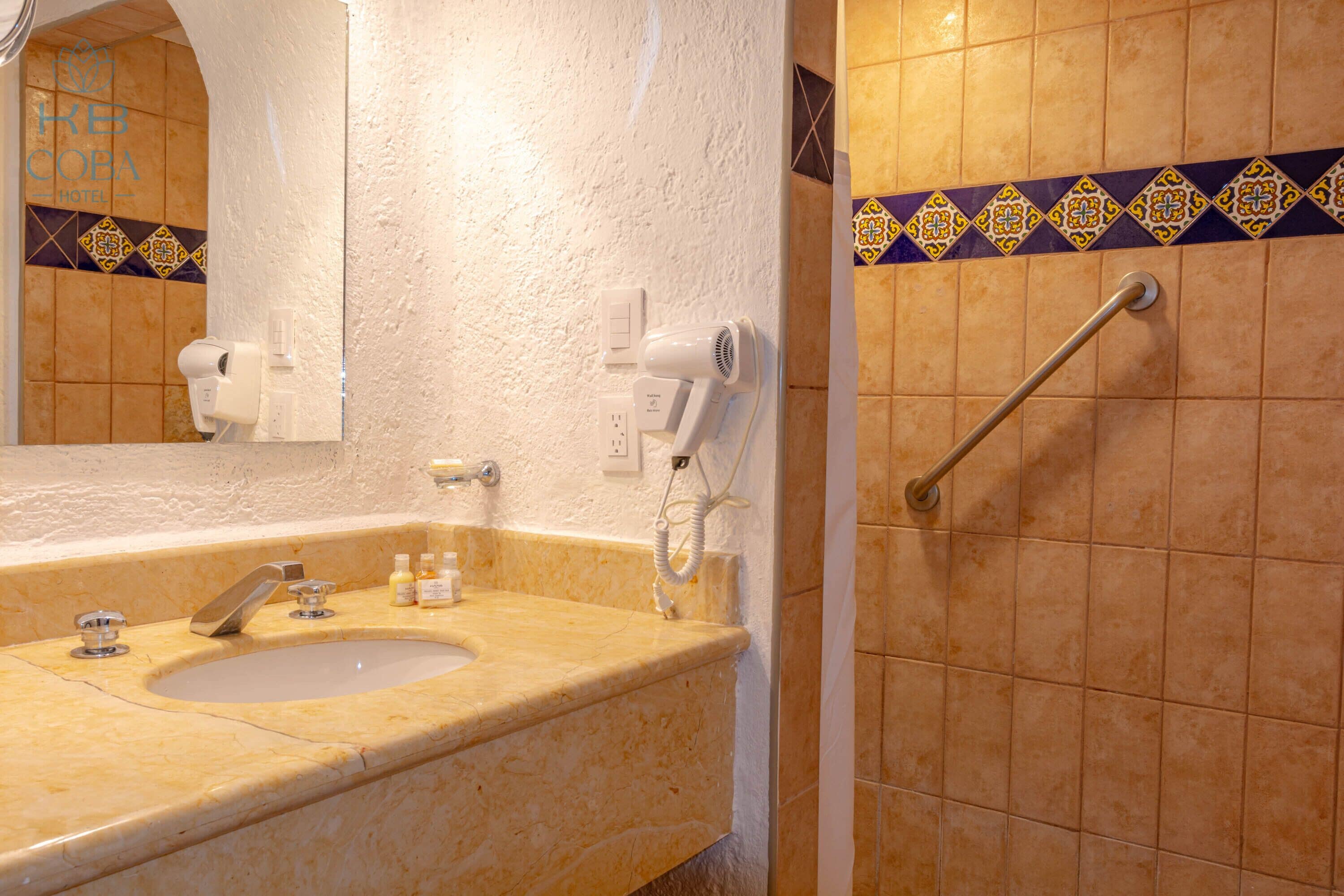 A bathroom with a sink, mirror, hairdryer, and hand dryer.