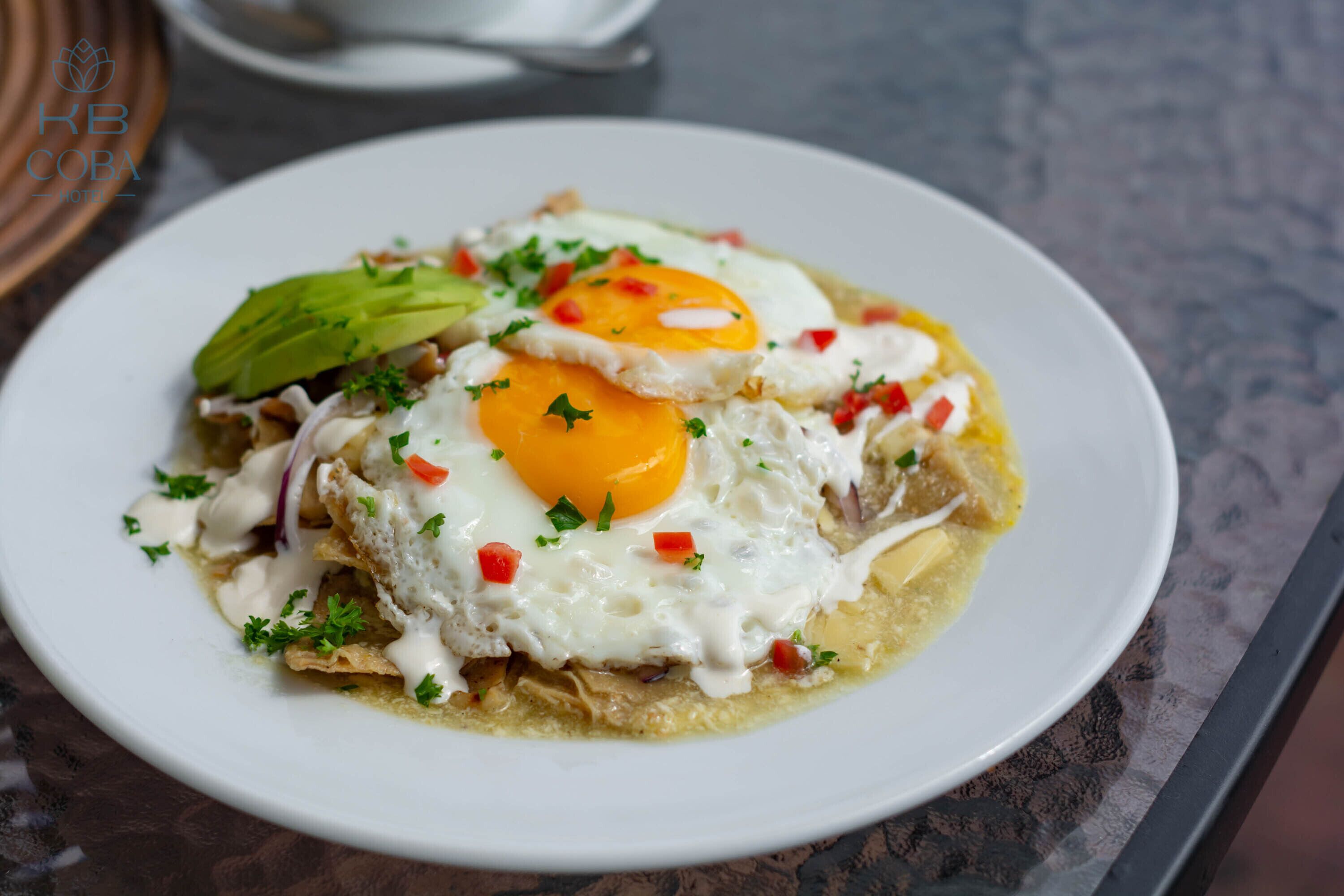 A plate of food with eggs, avocado, and red peppers.