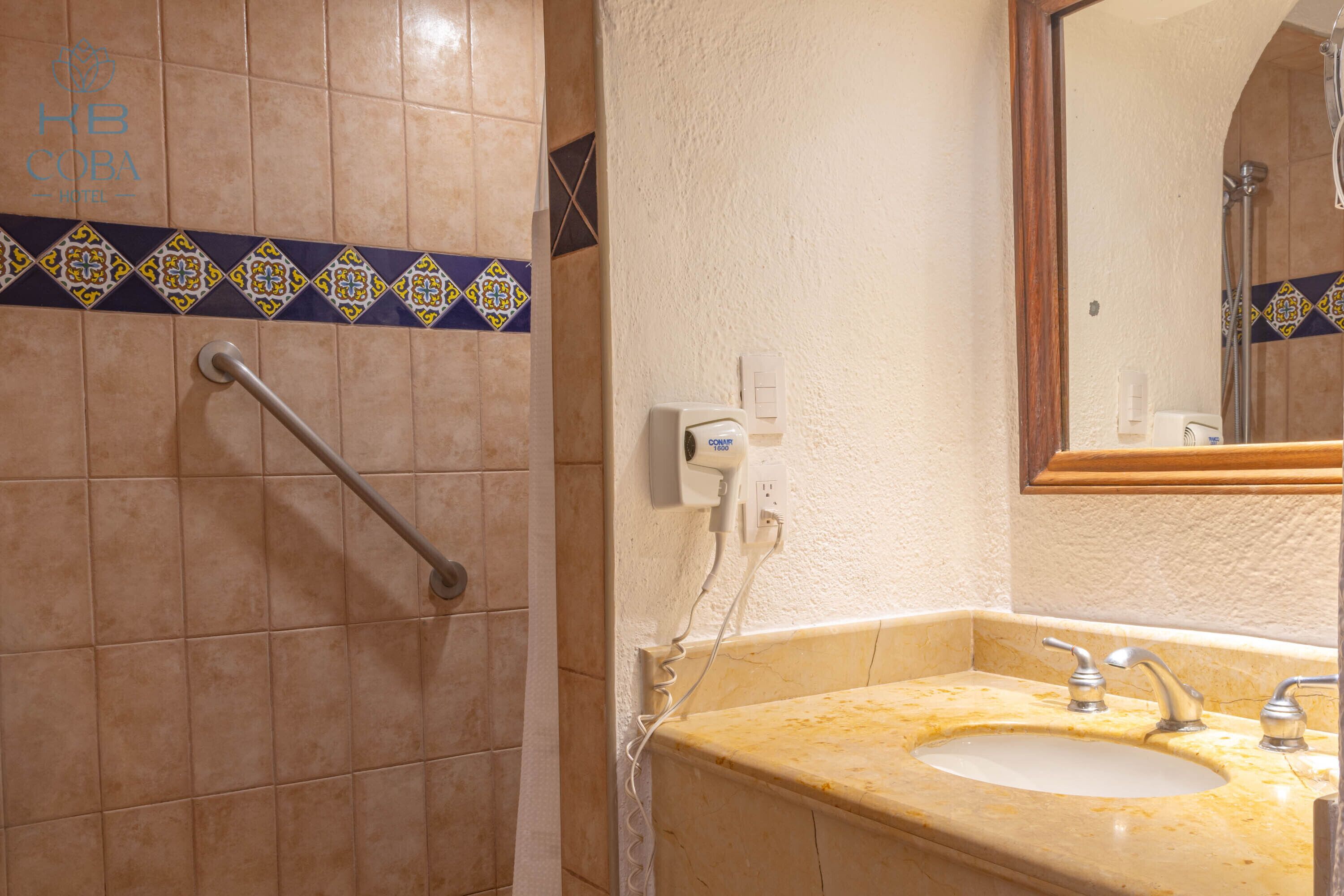 A bathroom with a sink, mirror, and handrail.
