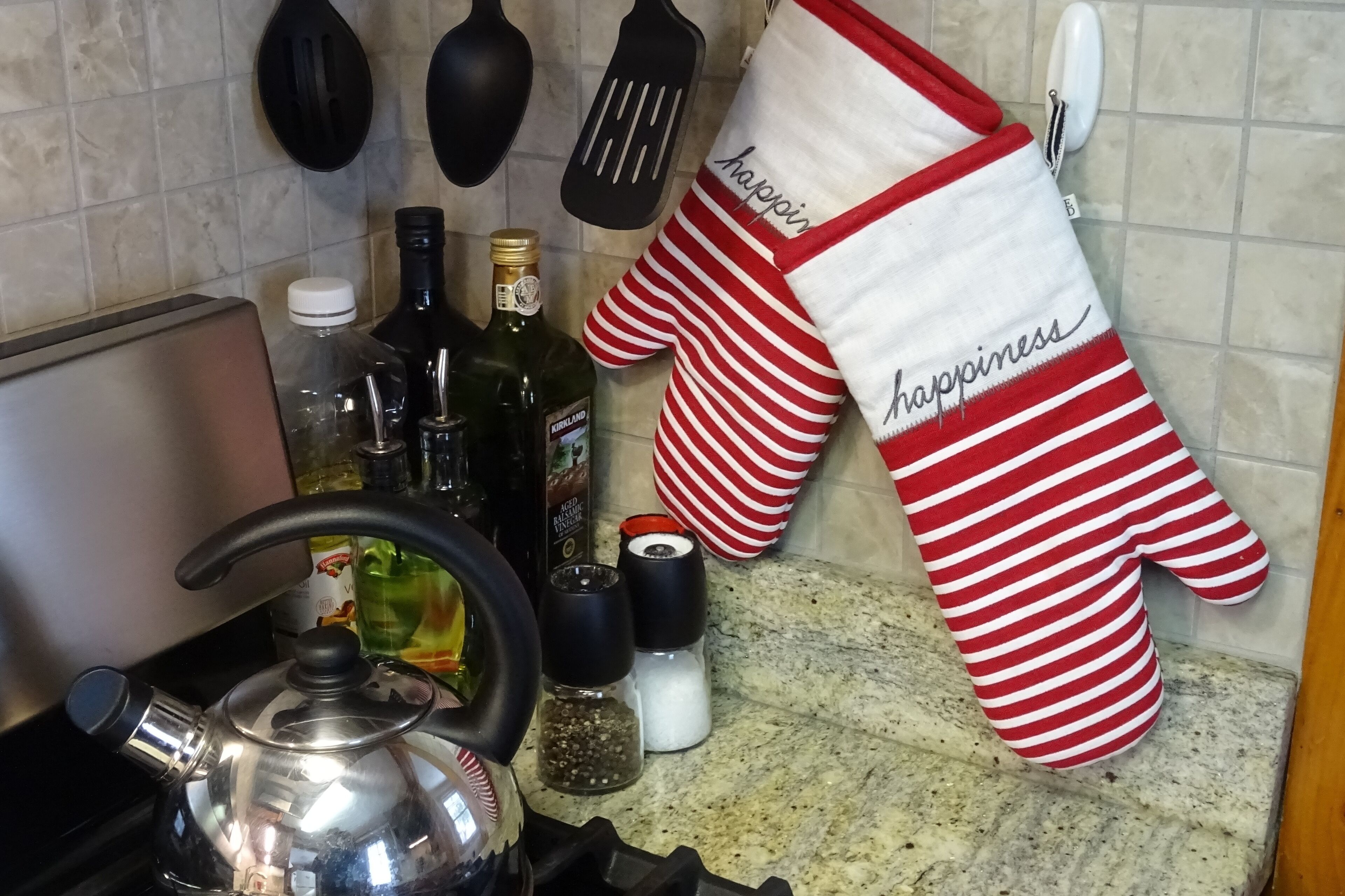 Cuina amb batedora, ampolles i una protecció per al forn a ratlles penjada a la paret.