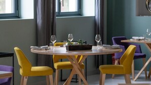 Ein Essbereich mit einem runden Tisch, gedeckt für vier Personen, gelben Stühlen und einer kleinen Pflanze als Tischdekoration.