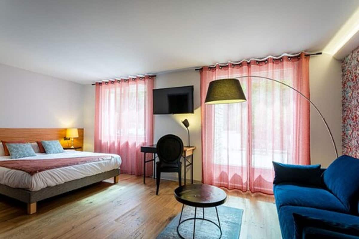 Una habitación de hotel con cama, escritorio, silla, sofá y televisor.