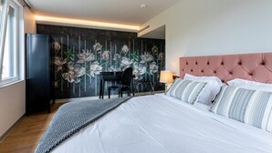 Ein modernes Hotelzimmer mit einem großen Bett, einem Schreibtisch und einer dunkel gemusterten Tapete.