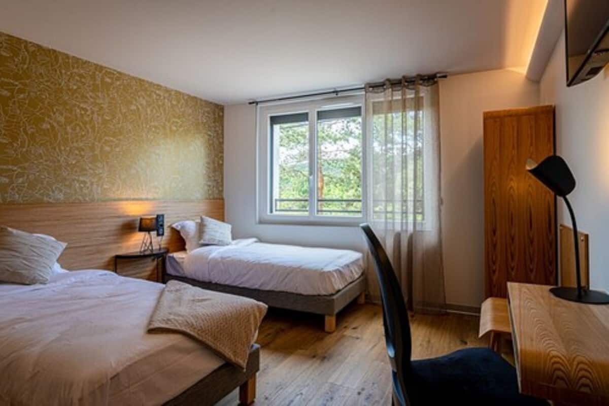 Un dormitorio con dos camas, un armario de madera, un escritorio y una silla.