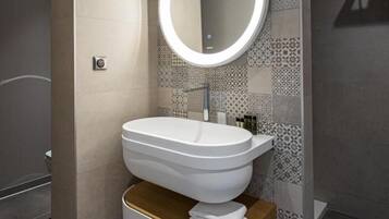 A modern bathroom with a round mirror, a white sink, and a wooden storage unit.