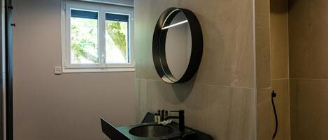 A modern bathroom with a built-in sink, a large mirror, and a window providing natural light.