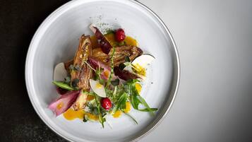 A white plate with a dish of food, including meat, vegetables, and sauce.