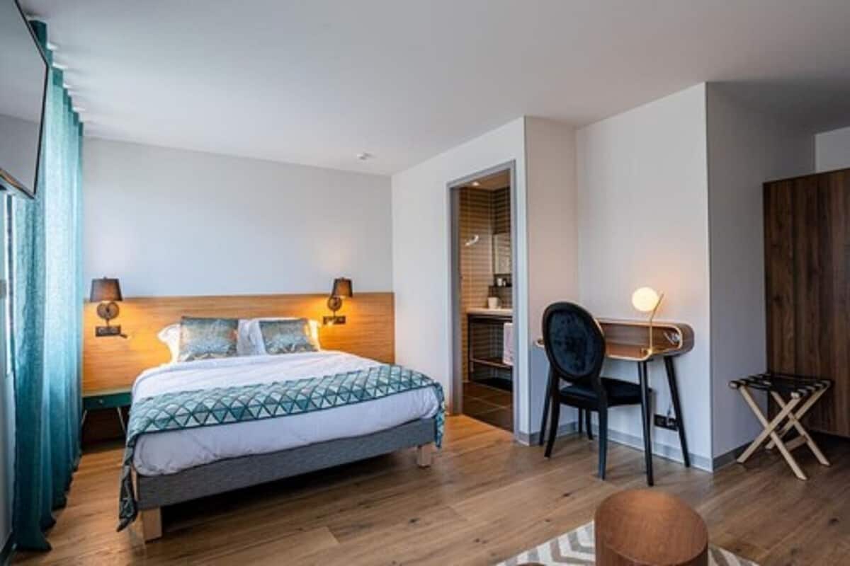 Un dormitorio moderno con una cama, lámparas de noche, una silla y una mesita.