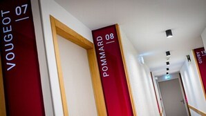Ein Hotelkorridor mit roten und weißen Schildern, die Zimmernummern angeben.