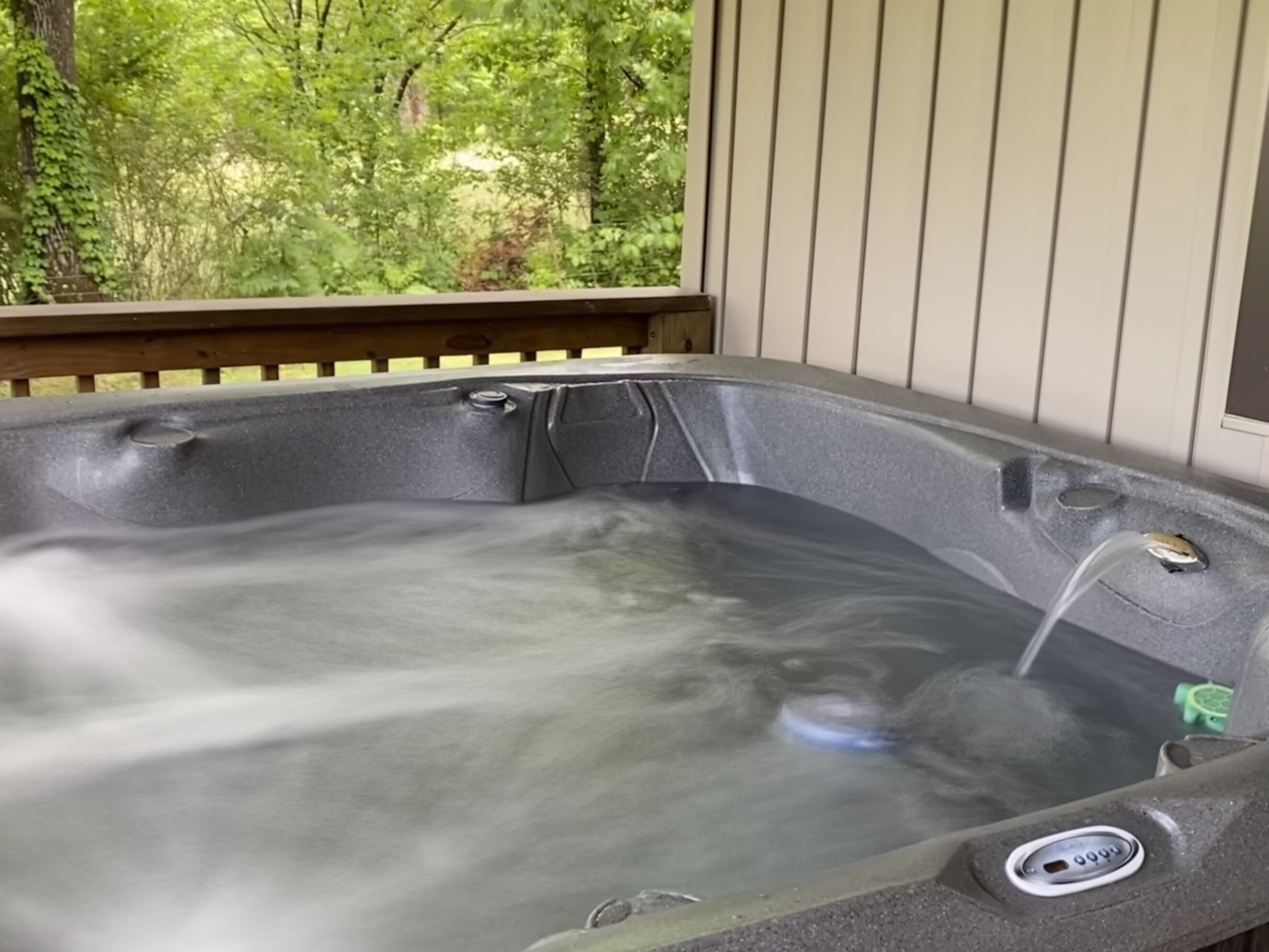 Ein Whirlpool mit einer Holzterrasse und Blick auf viel Grün.