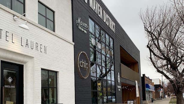 En moderne bygning med skiltning for '155 MAVEN DISTRICT' og 'CHARTEL LAUREN'.