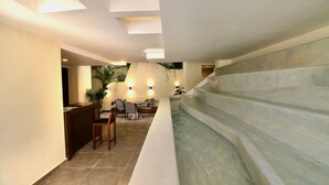 A modern interior with a reception desk, seating area, and a water feature.