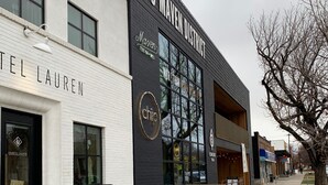 En moderne bygning med skiltning for '155 MAVEN DISTRICT' og 'CHARTEL LAUREN'.