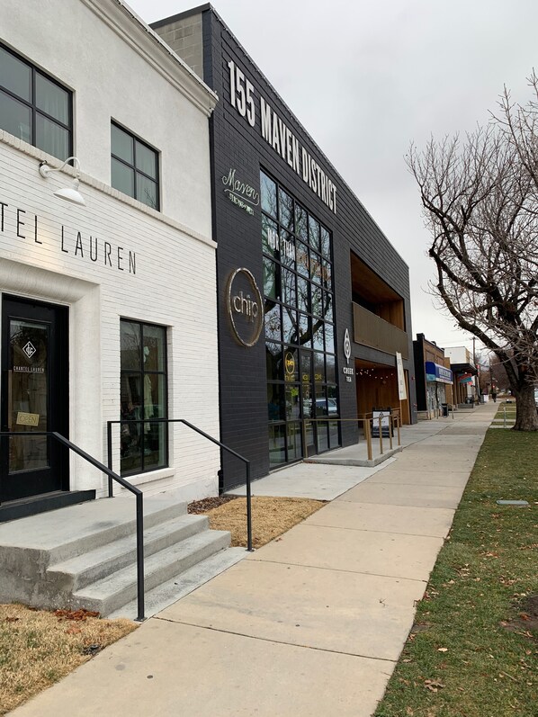 A modern building with a sign for '155 MAVEN DISTRICT' and 'CHARTEL LAUREN'.