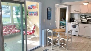 A kitchen with white cabinets, a stove, and a dining area with a table and chairs. - Belmar Shore House by the Sea!  
1.5 Blocks to Beach with 6 badges & Parking (Belmar)