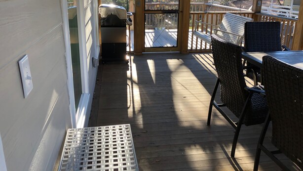 Un espace extérieur abrité, doté d’une terrasse en bois, de meubles en osier et d’un barbecue.