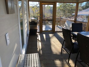 Un espace extérieur abrité, doté d’une terrasse en bois, de meubles en osier et d’un barbecue.