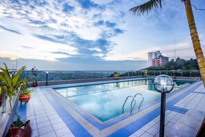 A rooftop pool with clear blue water, surrounded by potted plants and a palm tree. - Friendship Apartments (Kampala)