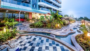 Un hotel con piscina, mobiliario exterior y exuberante jardinería.