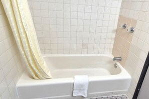 Un baño con bañera, cortina de ducha y paredes de azulejos.
