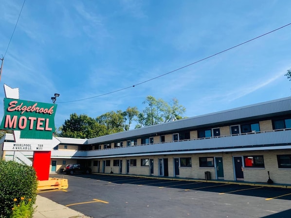 Un motel con un letrero, un estacionamiento y un edificio con múltiples ventanas.