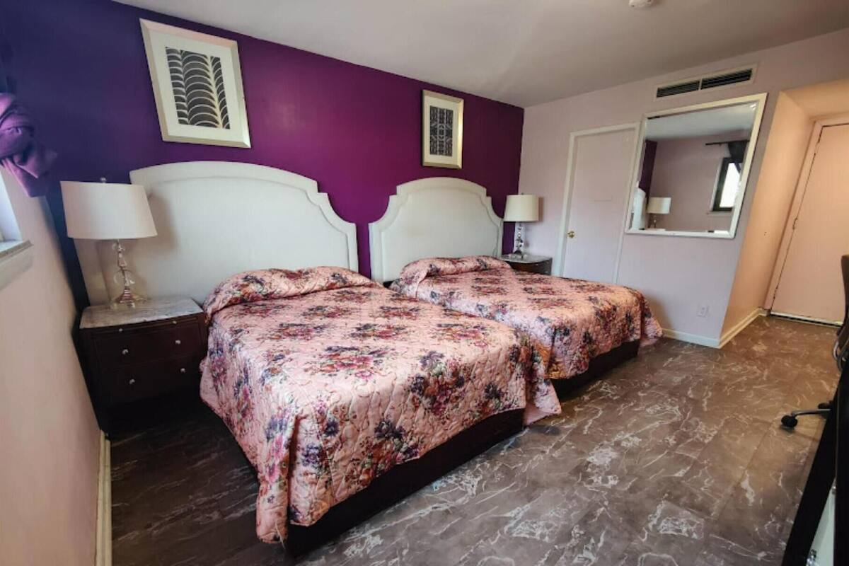Ein Schlafzimmer mit einem Bett, zwei Nachttischen, einem Schminktisch und einer Tür.