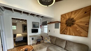 A modern living room with a sectional sofa, a coffee table, and a large wooden artwork on the wall. - El Bungaló Privado (San Clemente)