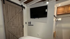 A bedroom with a bed, a mounted TV, and a wooden wardrobe. - El Bungaló Privado (San Clemente)