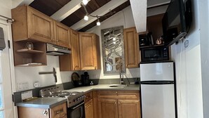 A kitchen with wooden cabinets, a stove, a refrigerator, and a microwave. - El Bungaló Privado (San Clemente)