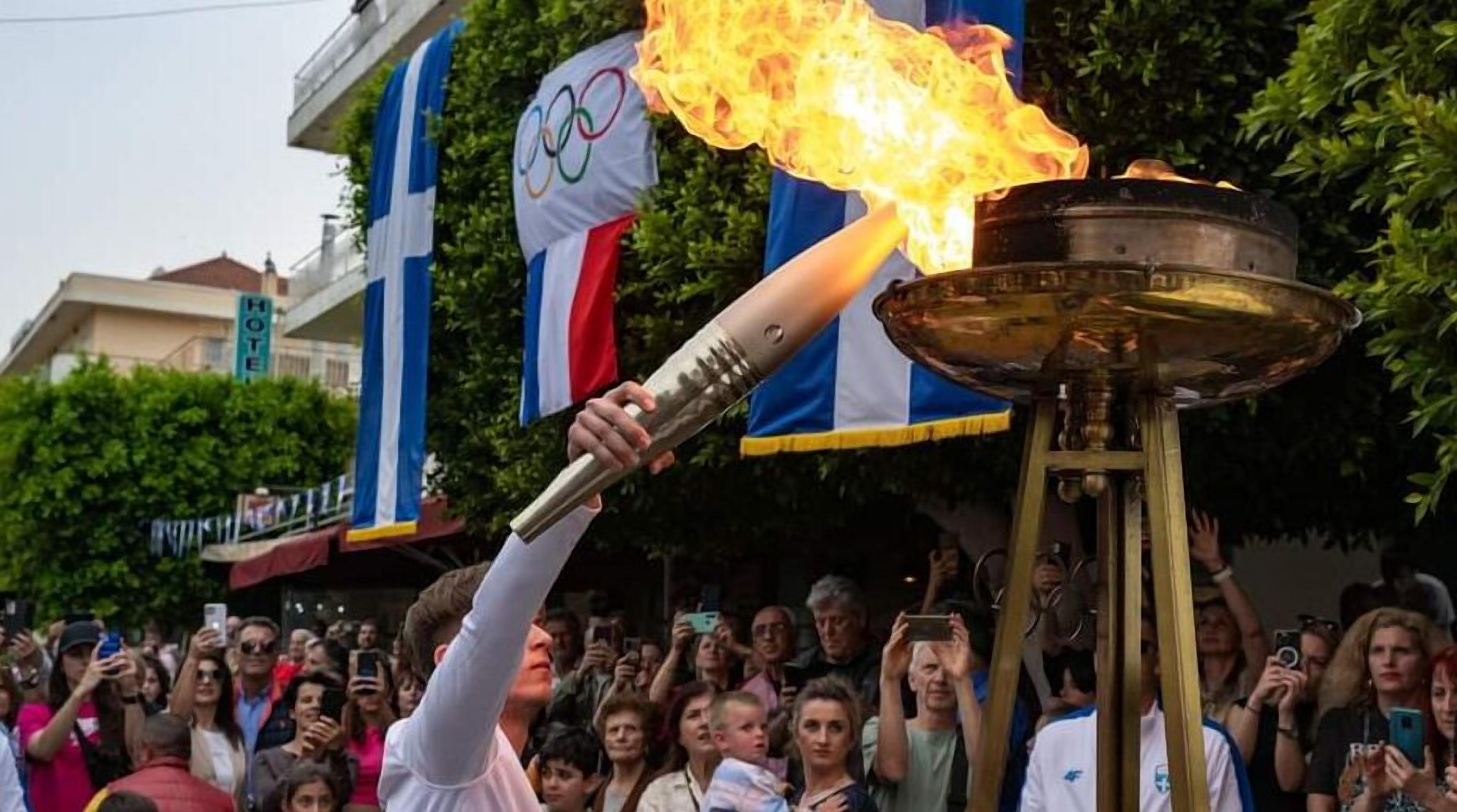 Une personne tenant une torche enflammée, entourée d’une foule et de drapeaux.