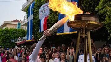Une personne tenant une torche enflammée, entourée d’une foule et de drapeaux.