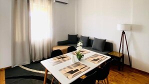 Una sala de estar moderna con una mesa de comedor, sillas negras, un sofá y una lámpara de pie.