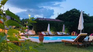 Un patio trasero con piscina, sillas de descanso y sombrillas.