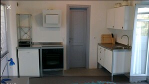 Eine kleine Küche mit Kühlschrank, Backofen, Spüle und Schränken.