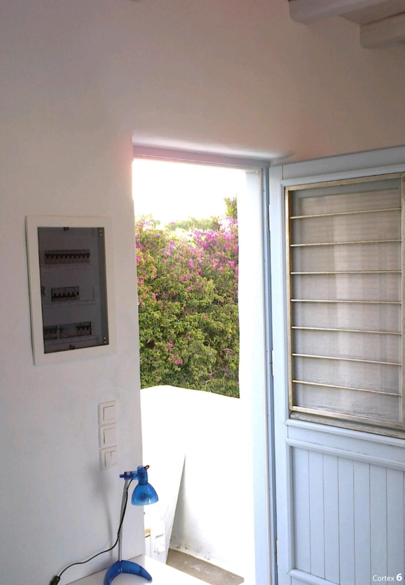 A room with a white door, a blue lamp, and a power outlet on the wall.