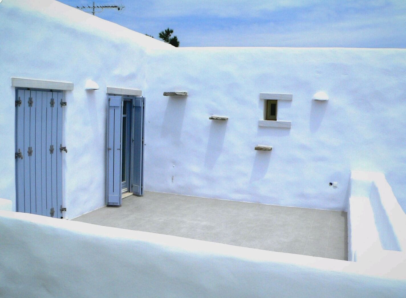 A white-walled building with a blue door and a small window.