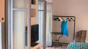 Ein Schlafzimmer mit einem Bett, einem Fernseher, einem Tisch und einem Kleiderständer.
