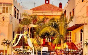 A courtyard with outdoor seating, a building with a red roof, and decorative plants.
