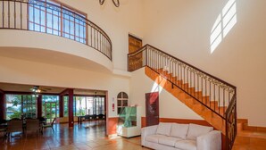 A spacious lobby with a curved staircase, a seating area, and large windows allowing natural light.