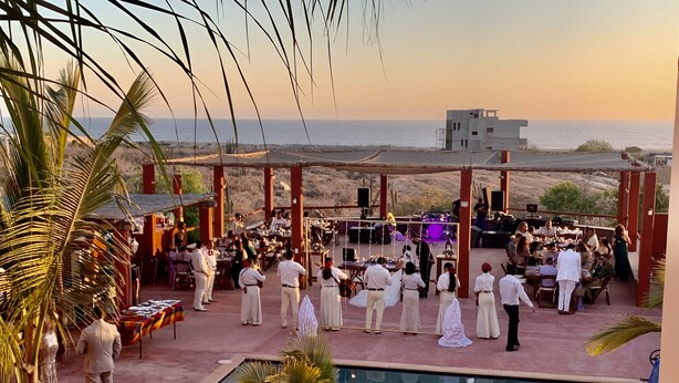 An outdoor wedding ceremony with a pool and palm trees.