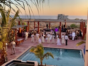 Una ceremonia de boda al aire libre con piscina y palmeras.