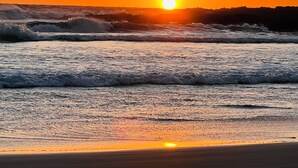 A sunset over the ocean with waves crashing onto the shore.