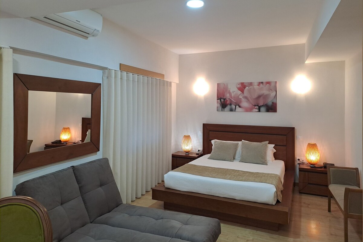 A modern bedroom with a large bed, bedside lamps, a mirror, and a ceiling light.